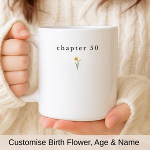 以下が含まれることがあります： 「chapter 50」の文字と小さな黄色の水仙のイラストが描かれた白いセラミックマグ。クリーム色のセーターを着た人がマグカップを持っています。画像の下部には「Customise Birth Flower, Age & Name」というテキストがあります。