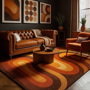 May include: A retro-style living room featuring a brown leather Chesterfield sofa, an orange armchair, and a round wooden coffee table. The room is decorated with abstract art and a rug with a bold, curved pattern in shades of orange and brown.