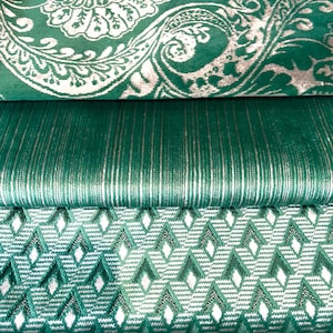 Op de afbeelding: Close-up van drie verschillende groene stofstalen. De bovenste stof heeft een groot bloemenpatroon in wit. De middelste stof heeft verticale strepen in wit. De onderste stof heeft een ruitpatroon in wit.