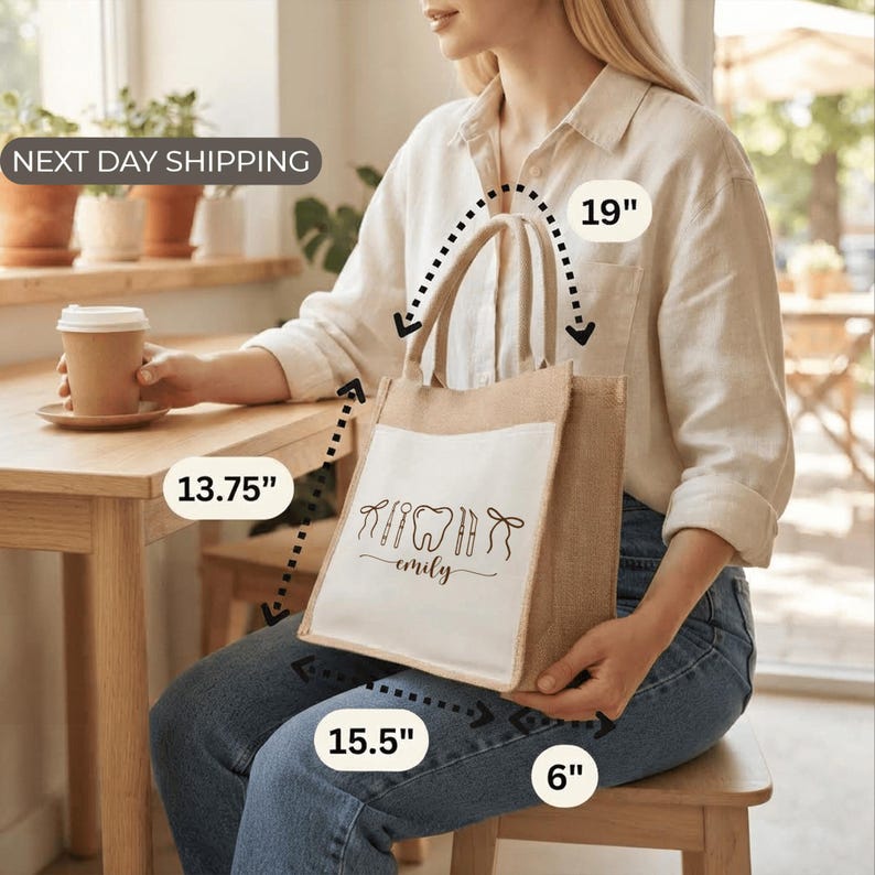 A woman sitting at a table with a coffee cup in front of her, holding a large tote bag with a printed design.