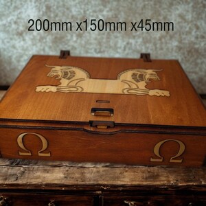 May include: A wooden box with a hinged lid, measuring approximately 7.9 x 5.9 x 1.8 inches. The box is stained a warm brown and features a laser-cut design of two lion-like creatures on the lid. The Greek letter Omega is on the front.