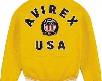 May include: A bright yellow jacket with the word "AVIREX" arched across the shoulders in black letters. Below the word "AVIREX" is a circular patch with the words "ALL AMERICANS ESTABLISHED 1975" and a graphic of the American flag. The word "USA" is below the patch.