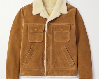 Könnte beinhalten: Braune Wildlederjacke mit cremefarbenem Shearling-Kragen und -Futter. Die Jacke hat zwei Brusttaschen und zwei Seitentaschen. Sie hat einen Knopfverschluss.