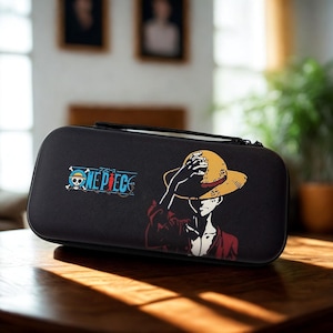 May include: Black carrying case featuring a graphic of a character from the anime series "One Piece." The design includes the show's logo and an illustration of a person wearing a straw hat. The case has a black handle and zipper.