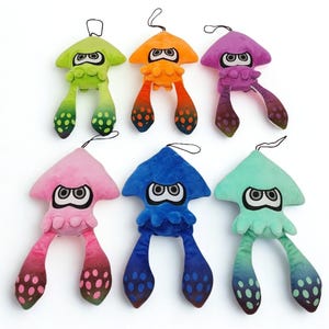 Peut inclure: Six peluches en forme de calmar aux couleurs vives : vert, orange, violet, rose, bleu et turquoise. Chaque calmar a de grands yeux stylisés et de longs tentacules avec des détails tachetés. Ils ont une boucle pour suspendre.