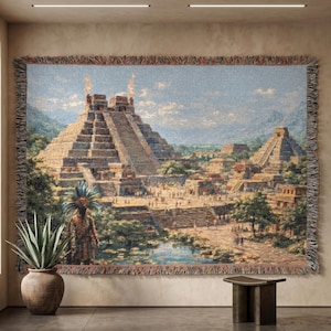 May include: A woven tapestry depicting an ancient Mayan city with pyramids, temples, and figures. The artwork features a detailed landscape with a blue sky, lush greenery, and a decorative fringe border. The tapestry is displayed on a wall.