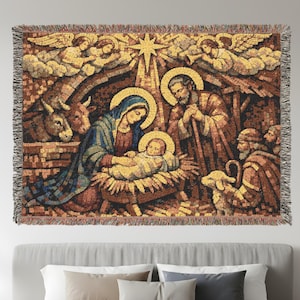 May include: Woven tapestry featuring the Nativity scene. The artwork shows Mary, Joseph, and baby Jesus, with angels, animals, and the Star of Bethlehem. The tapestry has a mosaic-like appearance with a fringed border, and is mainly brown, blue, and gold.
