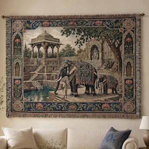 May include: A rectangular woven wall tapestry featuring a detailed scene of two elephants with ornate blankets standing near a stone pavilion and a pool of water. The border is decorated with floral motifs in blue, gold, and muted earth tones.