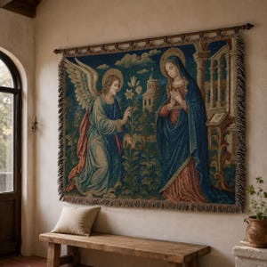 Horizontal woven blanket wall hanging featuring Archangel Gabriel kneeling before the Virgin Mary in an Annunciation scene, with lily flowers, halos, soft robes, garden landscape, old architecture, muted vintage colors, and fringed textile edges.
