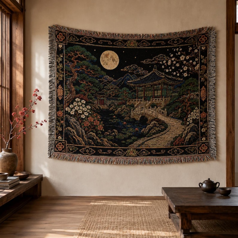 Korean palace tapestry wall hanging on a white background, showing a moonlit traditional garden with tiled pavilion, stone bridge, pond, pine tree, white blossoms, mountains, woven texture, and fringed edges.