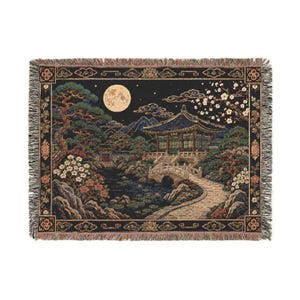 Korean palace tapestry wall hanging on a white background, showing a moonlit traditional garden with tiled pavilion, stone bridge, pond, pine tree, white blossoms, mountains, woven texture, and fringed edges.