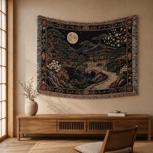 Korean palace tapestry wall hanging on a white background, showing a moonlit traditional garden with tiled pavilion, stone bridge, pond, pine tree, white blossoms, mountains, woven texture, and fringed edges.