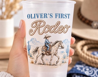 May include: A frosted plastic cup featuring the blue text OLIVER'S FIRST and the brown rope-style text Rodeo. Below, a graphic shows a child in a cowboy hat riding a horse through a desert landscape with blue mountains and cacti.
