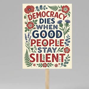 May include: A rectangular sign with the text "DEMOCRACY DIES WHEN GOOD PEOPLE STAY SILENT" in red and blue lettering. The sign is decorated with floral and botanical illustrations in red, green, and blue. It is mounted on a wooden stick.