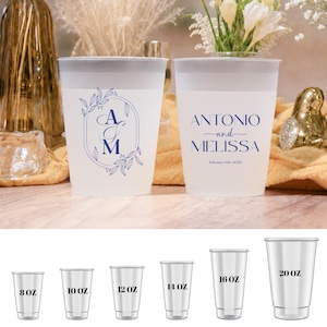 May include: Two frosted plastic cups with blue text and floral designs. One cup has the initials "A & M" inside a floral frame. The other cup reads "ANTONIO and MELISSA" with a date. Below are cups in 8, 10, 12, 14, 16, and 20 oz sizes.