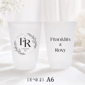 May include: Two frosted plastic cups with black text. One cup has the initials "FR" inside a floral wreath, with the date "11 April, Sunday 2026". The other cup has the names "Franklin & Roxy". The design is labeled "A6".