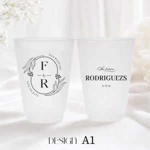 May include: Two frosted plastic cups with black text and designs. One cup features the initials "F & R" inside an oval with floral accents and the words "Our Wedding" and "Save the Date." The other cup says "The future RODRIGUEZ" and a date.