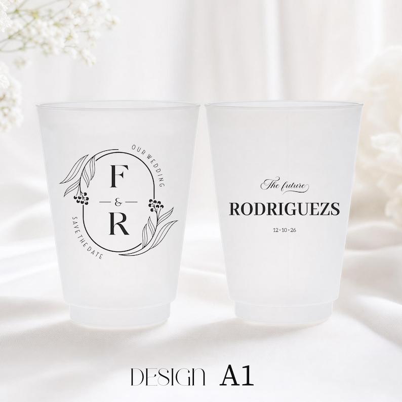 May include: Two frosted plastic cups with black text and designs. One cup features the initials "F & R" inside an oval with floral accents and the words "Our Wedding" and "Save the Date." The other cup says "The future RODRIGUEZ" and a date.