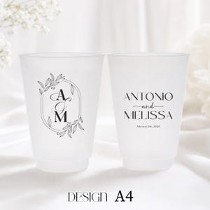 May include: Two frosted plastic cups with black text and designs. One cup features the initials "A" and "M" inside an oval with floral accents. The other cup has the names "Antonio and Melissa" and the date "February 11th, 2026". The design is labeled "DESIGN A4".