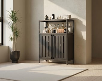 Puede incluir: Un mueble gris oscuro con dos puertas y una balda superior, lleno de varios frascos y tarros. Una planta alta en maceta se encuentra a la izquierda, y una alfombra blanca está en primer plano. El mueble tiene un diseño de puerta de listones.