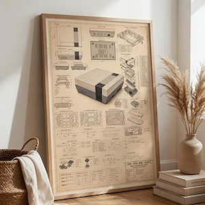 May include: A framed technical blueprint poster featuring a detailed schematic of a home video game console. The print displays various orthographic views, an exploded assembly diagram, circuit board layouts, and technical text in a sepia tone.