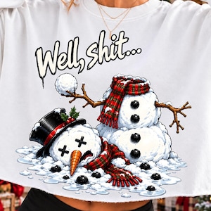 May include: A white long-sleeve sweatshirt featuring a graphic of a melted snowman wearing a black top hat and a red and green plaid scarf. The snowman has X-shaped eyes and an orange carrot nose. The text "Well, shit..." is printed above.