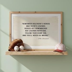 Op de afbeelding: Een ingelijste print met de tekst: REMEMBER KID, THERE'S HEROES AND THERE'S LEGENDS. HEROES GET REMEMBERED BUT LEGENDS NEVER DIE. FOLLOW YOUR HEART KID, AND YOU'LL NEVER GO WRONG. - The Sandlot. Een bruine honkbalhandschoen en een pet.