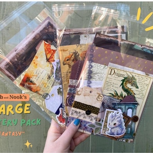 May include: A collection of fantasy-themed paper ephemera and stickers inside clear plastic sleeves. The items feature illustrations of dragons, griffins, and magical creatures, with text including "Nib and Nook's LARGE MYSTERY PACK FANTASY" and "The Dragon of Myth."
