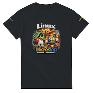 May include: Black t-shirt with a colourful graphic. The design shows a penguin and a computer screen in a battle scene, with the text "Linux VS Microslop" and the phrase "Blue Screens & Broken Dreams!"