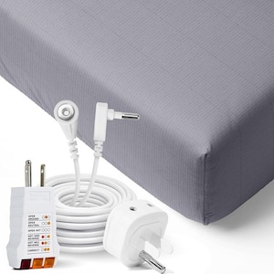 May include: A white grounding cable with a coiled cord, two plug adapters, and a plug-in electrical outlet tester. The tester has indicator lights and text. The background is a gray fitted sheet.
