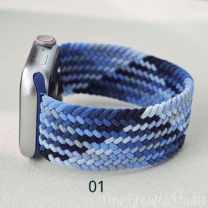 Könnte beinhalten: Geflochtenes Apple Watch Armband in Blautönen, darunter Marineblau, Hellblau und Weiß. Das Armband ist an einer silbernen Apple Watch befestigt. Die Nummer "01" ist unten im Bild aufgedruckt.