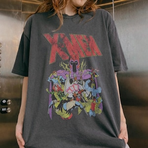 May include: Dark gray X-Men t-shirt featuring a distressed red logo and a colorful graphic of several comic book characters. The shirt has short sleeves and a crew neck.