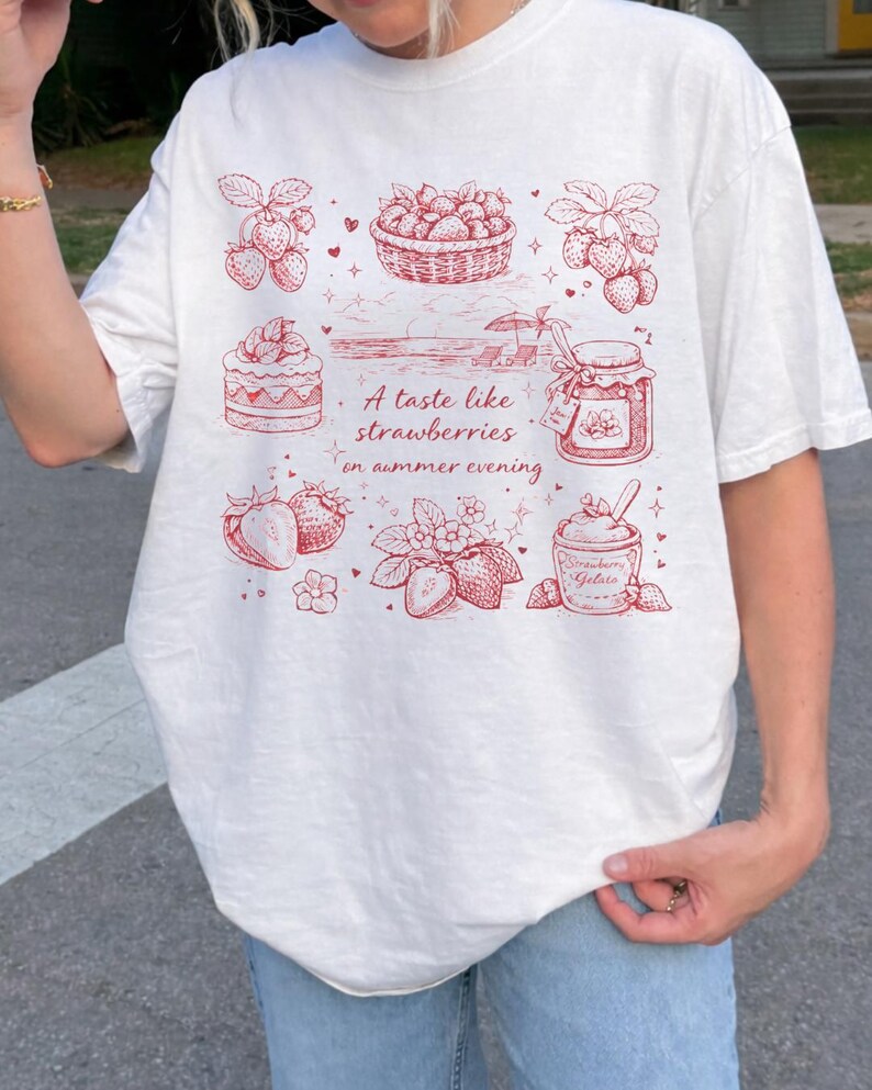 May include: White t-shirt with a red illustration of strawberries, a basket of strawberries, a jar of jam, and strawberry gelato. The text "A taste like strawberries on summer evening" is also printed on the shirt.