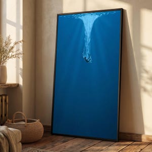 May include: A rectangular wall art print in a thin black frame featuring a deep blue ocean scene. The image depicts a silhouette of a person diving into the water, creating a white splash at the surface with light rays filtering down into the depths.