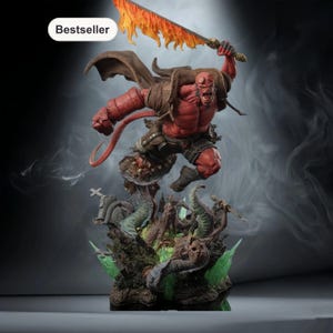 May include: A red Hellboy statue with a flaming sword, poised in a dynamic action pose. The figure is detailed with a tail, horns, and a muscular build. The base features a graveyard scene with green and brown elements. The word "Bestseller" is in a white oval.