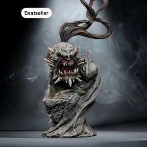 May include: A detailed statue of a monstrous creature with a menacing expression. The figure has a green complexion, sharp teeth, and spiky protrusions. The statue is set against a smoky, dark background, with the word "Bestseller" in a white oval.
