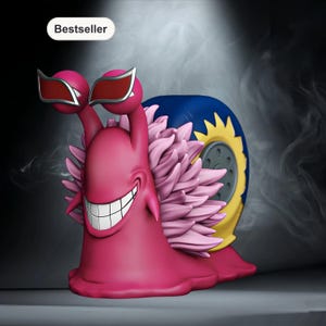 Può includere: Una statuetta a forma di lumaca rosa con occhiali da sole e un grande sorriso. La lumaca ha un guscio blu e giallo e un volant rosa. La parola "Bestseller" è in un ovale bianco nell'angolo in alto a sinistra.
