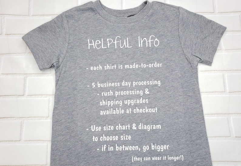 以下が含まれることがあります： グレーのTシャツに、白い文字で「HELPFUL Info」と書いてあり、処理時間、配送のアップグレード、サイズに関する情報が記載されています。