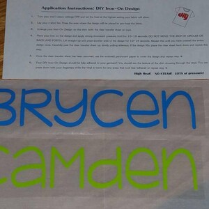 May include: Two iron-on labels with the names Brycen and Camden. The names are in blue and green lettering on a white background.