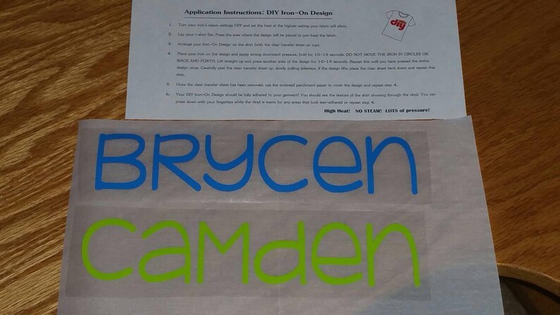 May include: Two iron-on labels with the names Brycen and Camden. The names are in blue and green lettering on a white background.
