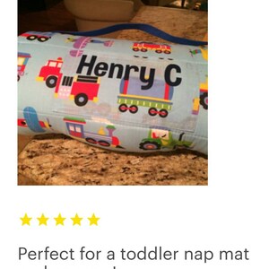 May include: A blue and white nap mat with a colorful train and truck design. The mat has a personalized name tag that reads "Henry C".