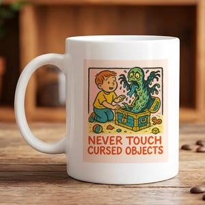 May include: White ceramic mug featuring a colorful illustration of a boy and a monster emerging from a treasure chest. The text "NEVER TOUCH CURSED OBJECTS" is printed below the image. The mug has a curved handle.