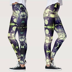 May include: A pair of black leggings with a colorful, abstract print featuring a repeating pattern of moons, stars, and other celestial imagery. The print is in shades of purple, blue, and yellow.