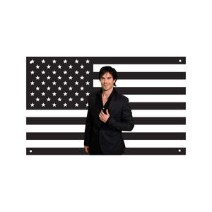 May include: A black and white American flag with a man in a black suit standing in front of it. The flag has white stars on a black background in the upper left corner and black and white stripes.