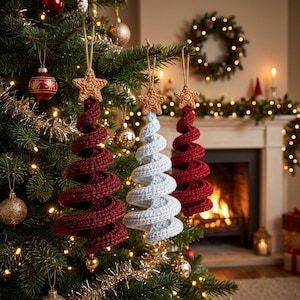 May include: Three spiral-shaped Christmas tree ornaments made of crocheted yarn. Two ornaments are deep red and one is light blue. Each ornament features a small, textured, tan-colored crocheted star at the top and a gold bead at the bottom.