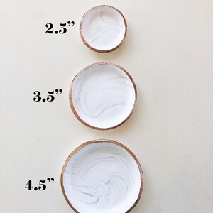 May include: Three small, round bowls with white interiors and brown rims are arranged vertically. The bowls measure 2.5 inches, 3.5 inches, and 4.5 inches in diameter. The white interiors have a marbled effect.