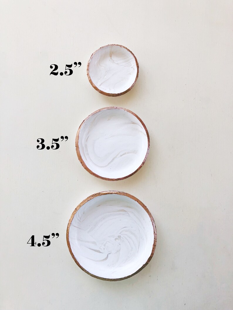 May include: Three handmade decorative bowls in varying sizes. The smallest bowl is 2.5 inches in diameter, the medium bowl is 3.5 inches, and the largest bowl is 4.5 inches. Each bowl has a white interior with a marbled effect and a brown rim.