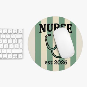 May include: Round mousepad with a green and cream striped background. The word "NURSE" is printed in black, with a stethoscope graphic and the text "est 2026". A white computer mouse rests on the pad.