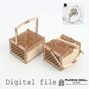 May include: Two light-coloured wooden thread organisers with laser-cut lattice side panels and swinging handles. Each box contains multiple vertical dividers with numbered holes for embroidery floss. Includes an inset image of floral embroidery.