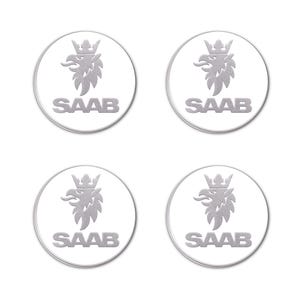 Könnte beinhalten: Vier silberfarbene Saab-Embleme. Jedes Emblem zeigt einen stilisierten Greif mit einer Krone über dem Kopf, eingebettet in einen weißen Kreis. Das Wort "SAAB" ist in einer serifenlosen Schrift unter dem Greif gedruckt.